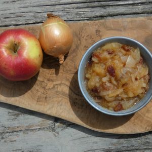 a bowl of food and an apple on a cutting board